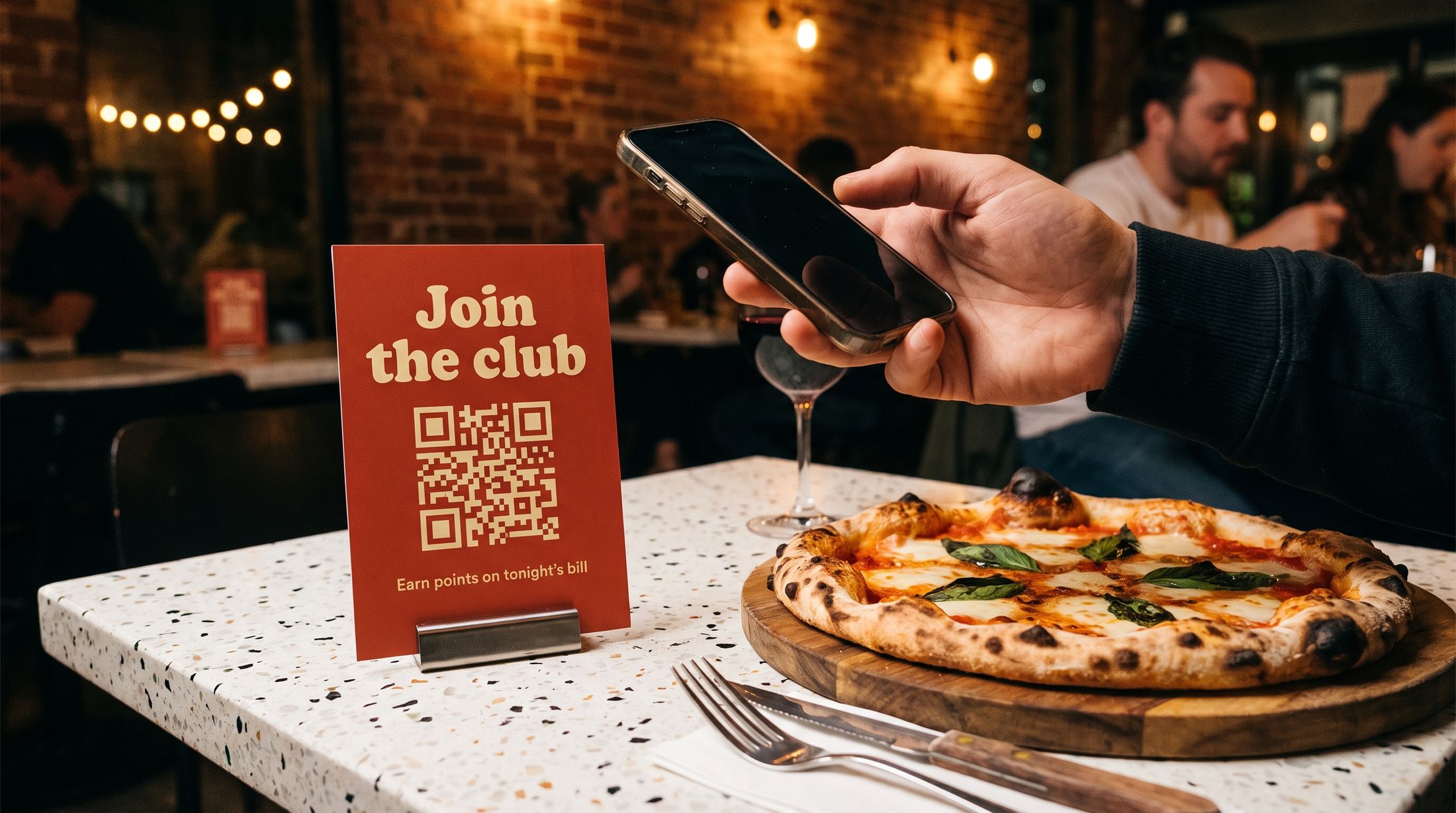 A Join the club table talker with a QR code beside a margherita pizza